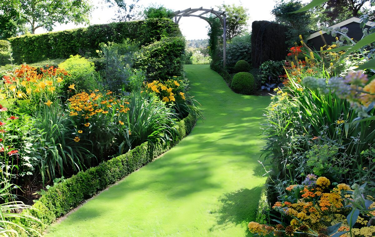Allée en pente recouverte d'herbe et entourée de fleurs