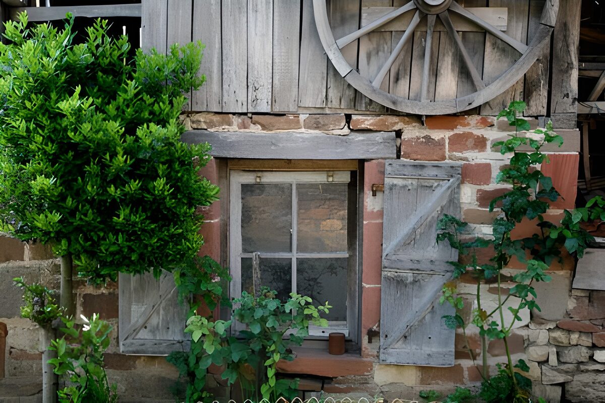 Vieille ferme française avec volets et roue accrochée en façade version 1