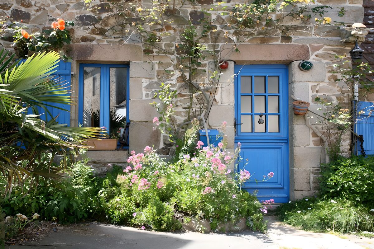 Maison française avec fenêtres aux volets bleus diverses plantes et fleurs